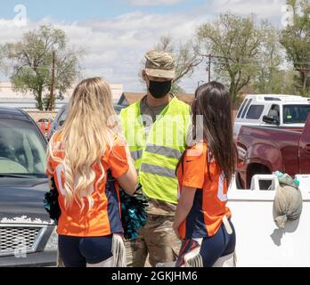 U.S. Army Sgt. James Hines, a cavalry scout assigned to 3rd Squadron, 61st Calvary Regiment, talks with cheerleaders of the Denver Broncos at the Community Vaccination Center (CVC) at the Colorado State Fairgrounds in Pueblo, Colorado, May 4, 2021. The Denver Broncos mascot and cheerleaders visited the Pueblo CVC to support Soldiers and community members. U.S. Northern Command, through U.S. Army North, remains committed to providing continued, flexible Department of Defense support to the Federal Emergency Management Agency as part of the whole-of-government response to COVID-19. Stock Photo