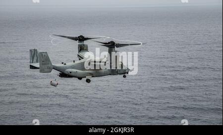 A U.S. Marine Corps MV-22B Osprey assigned to Marine Medium Tiltrotor Squadron (VMM) 262, performs hoist operations off the coast of Ie Shima, Okinawa, Japan, May 6, 2021. Hoist operations were conducted in order to train crew and pilots to conduct specialized contingency missions. Stock Photo