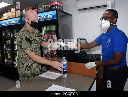 CAMP LEMONNIER, Djibouti (May 7, 2021) - U.S. Navy Capt. Kyle Schuman, commanding officer, Camp Lemonnier, Djibouti, makes the first purchase from Camp Lemonnier’s newest Navy Exchange, CLU Mart, May 7, 2021. Camp Lemonnier is an operational installation that enables U.S., allied and partner nation forces to be where and when they are needed to ensure security in Europe, Africa and Southwest Asia. Stock Photo