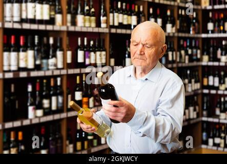 man chooses between red and white wine Stock Photo