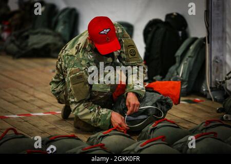 A U.S. Army Paratrooper assigned to the 82nd Airborne Division checks a parachute during Swift Response 21 in Boboc, Romania, May 10, 2021. Swift Response 21 is a Defender 21 linked exercise, an annual large-scale US Army-led, multinational, joint exercise designed to build readiness and interoperability between US, NATO, and partner militaries. Stock Photo