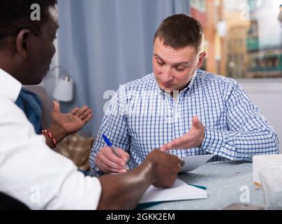 Two serious men analysing documents at home Stock Photo