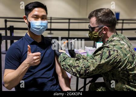 U.S. Army 2nd Lt. Charlson Ro, a Korean-American military intelligence officer and Massachusetts Institute of Technology student, originally from Dededo, Guam, receives his second COVID-19 vaccination from U.S. Navy Petty Officer 3rd Class David Lamison, a hospital corpsman assigned to the Boone Clinic, Portsmouth, Virginia, at the Community Vaccination Center at the Hynes Convention Center in Boston, May 11, 2021. U.S. service members from across the country are deployed in support of the Department of Defense federal vaccine response operations. U.S. Northern Command, through U.S. Army North Stock Photo