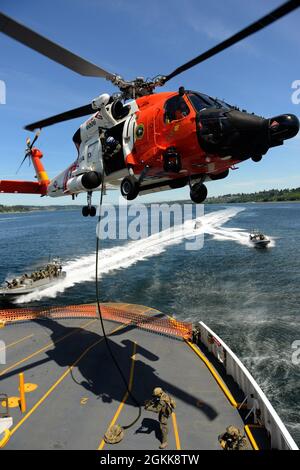 Coast Guard crews with Maritime Security Response Team West use multiple assets, working with a Sector Columbia River MH-60 Jayhawk helicopter crew, to board Pierce County Ferry Steilacoom II during a tactical exercise on May 13 near Fox Island, WA. This exercise was held to display the proficiencies and multi-unit interoperability of MSRT West in the event of an emergency threat. Stock Photo
