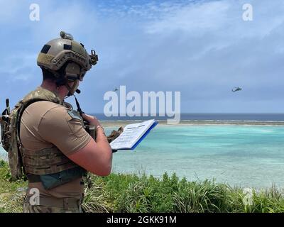 OKINAWA, Japan – A U.S. Army Green Beret assigned to 1st Battalion, 1st Special Forces Group (Airborne) communicates with two U.S. Navy Sikorsky HH-60 helicopter with the Helicopter Sea Combat Squadron 85 during Close Air Support Training May 13, 2021. Green Berets trained using the 5-line Call for Fire, directing the aircraft to targets in order to support ground force elements. Stock Photo
