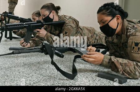 U.S. Army Reserve Spc. Jody Padgett, left, and Pvt. Dulce Higareda, both in the 647th Regional Support Group (RSG), 416th Theater Engineer Command, based in Wichita, Kan., insert empty magazines in their assigned rifles unsupported during a new rifle qualification class at the Lanny J. Wallace Reserve Center in Wichita, May 14, 2021. The Soldiers practiced employing empty magazines on their own while transitioning between the standing, kneeling and prone positions. Stock Photo