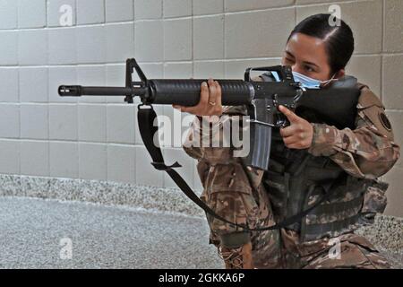 U.S. Army Reserve Spc. Valerie Rico, 387th Human Resources Company, 89th Sustainment Brigade, 451st Expeditionary Sustainment Command, 79th Theater Sustainment Command based in Wichita, Kan., right, assumes an unsupported kneeling position with her assigned rifle with an empty magazine during a new rifle qualification class at the Lanny J. Wallace Reserve Center in Wichita, May 14, 2021. The Soldiers practiced this position and the  kneeling and prone positions and transitioning between each position while employing empty magazines on their own. Stock Photo
