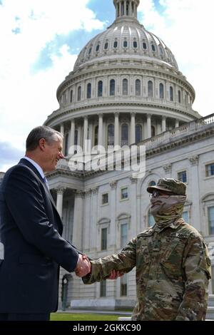 Massachusetts Governor Charlie Baker thanks Pfc. Marc Anthony Andino, a Chemical, Biological, Radiological, and Nuclear Specialist with the 272nd Chemical Company of the Massachusetts National Guard, for his service during the Capitol Response mission at the United States Capitol Building, in Washington, D.C., May 14, 2021. Since January, Army and Air National Guard units from around the country have provided ongoing security, communication, medical, evacuation, logistical and safety support to capital civil authorities. Stock Photo