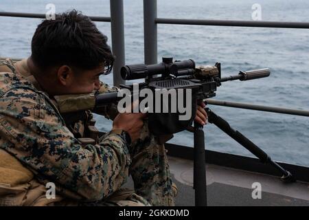 PACIFIC OCEAN (May 15, 2021) U.S. Marine Corps Sgt. Aaron Palomino, a scout sniper assigned to 1st Battalion, 1st Marines, 11th Marine Expeditionary Unit (MEU), from San Diego, prepares to fire an M27 Infantry Automatic Rifle aboard amphibious assault ship USS Essex (LHD 2), May 15. Sailors and Marines of the Essex Amphibious Ready Group (ARG) and the 11th MEU are underway off the coast of southern California. Stock Photo