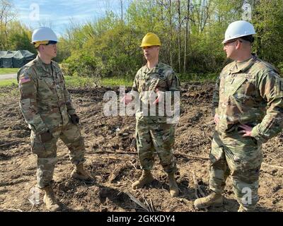 New York Army National Guard Capt. Christopher Baun, right, commander of the 152nd Engineer Company, and his executive officer, 1st Lt. James Spellman at left, brief Col. Jamey Barcomb, center, commander of the 153rd Troop Command with an update of construction operations at the National Guard Youngstown Local Training Area in Youngstown, N.Y., May 15, 2021 during unit annual training. The company returned to the field for collective training for engineer tasks after a year of virtual training, constructing an Army Combat Fitness Course, a Situational Training Exercise lanes course and a land Stock Photo