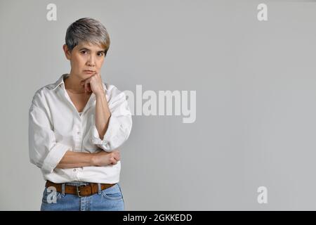 Image of thinking middle aged Asian woman standing isolated over white background Stock Photo