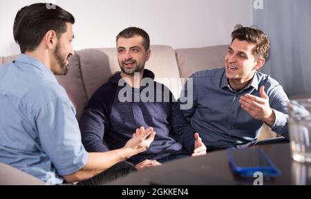 Three males having fun talking on couch Stock Photo