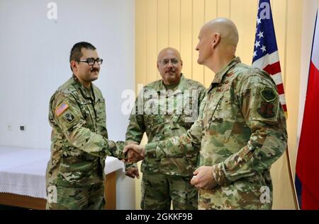 Air Force Maj. Gen. James Eifert (right), Florida National Guard adjutant general, presents Army Sgt. Anthony Jimenez (left) with a coin in a handshake to recognize his excellent performance at Forward Operating Site (FOS) Zagan, Poland, on May 15, 2021. Eifert thanks the Soldiers and states the importance of their roles during their deployment. Jimenez and Army Master Sgt. Jose Cardona (center) are assigned to the 50th Regional Support Group from Homestead, Florida, which is deployed to Poland to support Atlantic Resolve by providing management and base operations support at various FOSes thr Stock Photo