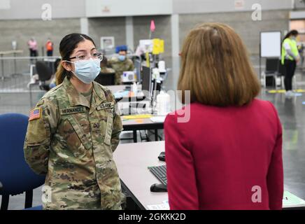 Oregon State Governor, Kate Brown, speaks to Oregon Army National Guard, Private First Class Rocio Hernandez, a vaccine registrar (left) at the Oregon Convention Center, Portland, Ore., May 18, 2021. Governor Brown stopped by to congratulate the team on giving their 500-thousandth dose that day. Stock Photo