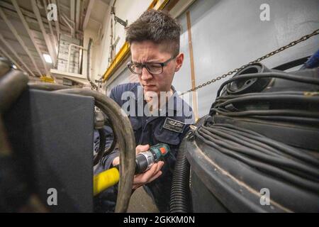 210517-N-TF178-1041  PACIFIC OCEAN (May 17, 2021) – U.S. Navy Electrician’s Mate Fireman Brandon Jerome performs maintenance on a battery charger aboard the amphibious assault ship USS Makin Island (LHD 8). The Makin Island Amphibious Ready Group and the 15th Marine Expeditionary Unit are conducting routine operations in the U.S. 3rd Fleet area of operations. Stock Photo