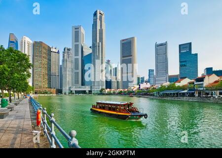 A tour boats cruising on the Singapore River past Boat Quay (r), in the background the high rise towers of banking district Raffles Place; Singapore Stock Photo