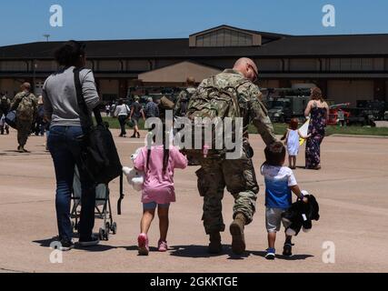 Tech. Sgt. Careen Lewis, 7 Equipment Maintenance Squadron aircraft structural maintenance NCO in charge, left, and Tech. Sgt. Justin Pitman, 317th Aircraft Maintenance Squadron crew chief, right, walk off of the flightline with their children Caiya, 4-years-old, and Luca, 2-years-old, at Dyess Air Force Base, Texas, May 15, 2021. Family members have access to a multitude of resources across the base to help them while their military spouses are deployed. Stock Photo