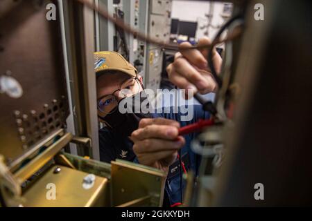 210520-N-IG124-1018 ATLANTIC OCEAN (May 20, 2021) Electronics Technician 3rd Class Jacob Dyke, from Kansas City, Missouri, uses a multimeter to check voltage levels on a tactical air navigation radio in a radio room aboard the Nimitz-class aircraft carrier USS Harry S. Truman (CVN 75) during sea trials after completing an extended carrier incremental availability. Sea trials include a comprehensive test of the ship’s systems and technologies in order to ensure the ship is ready to resume operations. Stock Photo