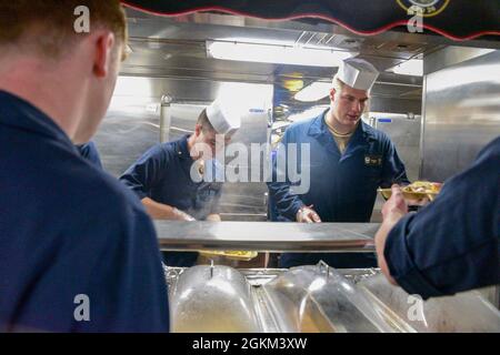 210521-N-MT581-1070     PACIFIC OCEAN (May. 21, 2021) Midshipmen from the U.S. Naval Academy serve lunch for the amphibious transport dock ship USS John P. Murtha (LPD 26) crew, May 21. John P. Murtha is underway conducting routine operations in U.S. Third Fleet. Stock Photo