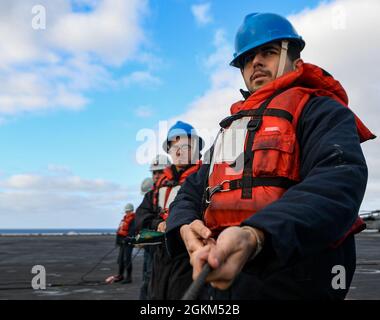 PACIFIC OCEAN (May 22, 2021) – U.S. Navy Seaman Noah Anderson, from Pittsburgh, holds a phone-and-distance line aboard the aircraft carrier USS Theodore Roosevelt (CVN 71) during a replenishment-at-sea, May 22, 2021. The Theodore Roosevelt Carrier Strike Group is on a scheduled deployment conducting routine operations in U.S. 3rd Fleet. Stock Photo