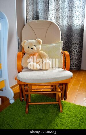 Teddy bear in rocking chair in children's room interior Stock Photo