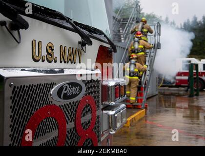 Sailors assigned to the Los Angeles-class fast-attack submarine USS Jacksonville (SSN 699) prepare to battle a simulated fire alongside Navy Region Northwest Fire and Emergency Services during training at Naval Base Kitsap-Bangor in Silverdale, Washington May 25, 2021. The training assesses Sailors’ ability to conduct integrated hands-on firefighting response procedures while combatting a shipboard casualty in port or under construction activity. Stock Photo