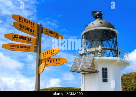 Cape Reinga in the far north of New Zealand. The historic lighthouse and a signpost pointing to other parts of the globe Stock Photo