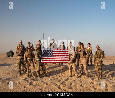 Joint terminal attack controllers assigned to the U.S. Air Force, Army, Navy and Marine Corps pose with an American Flag alongside Italian air force members at the end of joint/coalition training at Udairi Range Complex, Kuwait, May 26, 2021. For training, the U.S. armed forces joint terminal attack controllers guided Italian air force Eurofighter Typhoons to conduct close air support. Stock Photo