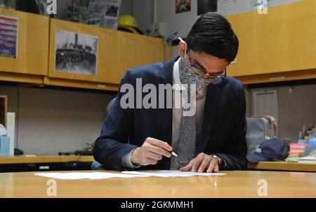 Ensign Atman Soni signs documents in the library of the Hampton Roads Naval Museum as part of his commissioning ceremony on the Battleship Wisconsin. The ceremony was facilitated by the museum, located next door to the museum ship in Downtown Norfolk, Virginia. Stock Photo