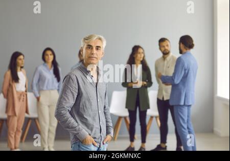 Portrait of confident middle-aged man in casual clothes background of other people. Stock Photo