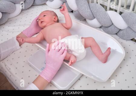 https://l450v.alamy.com/450v/2gkmnyx/the-doctor-weighs-a-newborn-baby-on-a-scale-uniformed-nurse-taking-measurements-of-the-child-weight-2gkmnyx.jpg