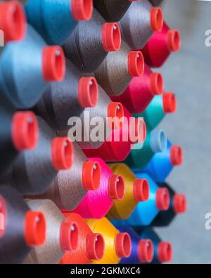 Colorful embroidery thread spool using in garment industry, row of multicolored yarn rolls, sewing material selling in the market Stock Photo