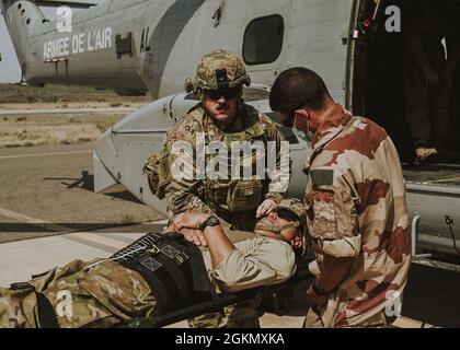 A soldier from Task Force Iron Gray and a French Air Force member load a simulated injured service member onto a French aircraft in support of the medical evacuation exercise May 31, 2021, at Chabelley Airfield, Djibouti. The French Air Force took initiative to provide their aircraft in order to transfer the simulated injured patients from Chabelley Airfield to Camp Lemonnier in Djibouti. Stock Photo