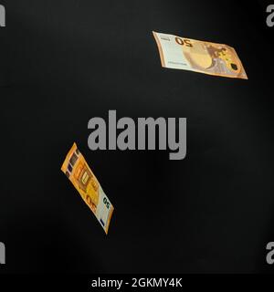 several euro bills fall, fly on a black background, happiness in money. new Stock Photo