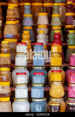 There are many jars of organic, natural honey on the counter for sale. Different honey, different colors in plastic cans are ready for sale at the hon Stock Photo