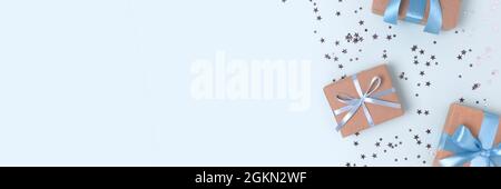 Banner with frame made of gift boxes with tied ribbons and silver confetti on a blue background. Stock Photo