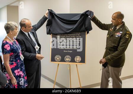 Lt. Gen. Gary M. Brito, U.S. Army Deputy Chief of Staff, G-1, right, and unveils a memorial plaque with the parents of Michael G. Sauro, a former Defense Ammunition Center hazardous material instructor who lost his life while deployed as a civilian in support of Operation Freedom’s Sentinel, during a building dedication ceremony at Camp Atterbury, Ind., June 3, 2021. Sauro’s mother, Christine Sauro, left, and father, Michael E. Sauro, were on-hand to help dedicate Building 444 on the installation to their son. Stock Photo