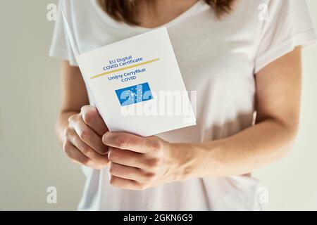 Woman holds covid-19 certificate in hands made in Poland. Vaccination in Europe Union for protection from coronavirus Stock Photo
