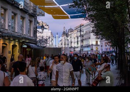 Pedestrians walk on a sidewalk near the Puerto del Sol, Madrid, Spain, September 2021 Stock Photo