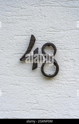 Metal house number 48 on a white stucco wall background, close up Stock Photo