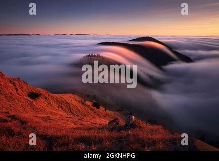 Mountain landscape above clouds at sunset in Slovakia with forest and sun Stock Photo