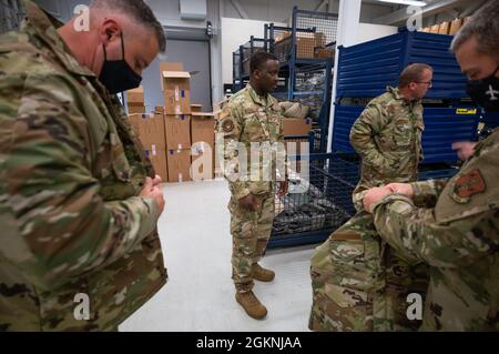 Staff Sergeant Salem Dogbe, Individual Equipment Element, 168th Wing Logistics Readiness Squadron, observes as fellow Airmen try on Operational Camouflage Pattern cold weather parkas at Eielson Air Force Base, Alaska, June 6th, 2021. Airmen from the 168th Wing, Alaska Air National Guard, are being issued their OCP cold weather parka, a vital part of their uniform when operating in an arctic environment. LRS is tasked with ensuring the Airmen of the 168th Wing are supplied with the clothing and equipment they require for mission success, especially in the sub-zero temperatures of Alaska. Stock Photo