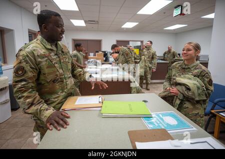 Staff Sergeant Salem Dogbe, Individual Equipment Element, 168th Wing Logistics Readiness Squadron, speaks with Airman First Class Zoe Gruben, Crew Chief, 168th Wing, at Eielson Air Force Base, Alaska, June 6th, 2021. Airmen from the 168th Wing, Alaska Air National Guard, are being issued their Operational Camouflage Pattern cold weather parka, a vital part of their uniform when operating in an arctic environment. LRS is tasked with ensuring the Airmen of the 168th Wing are supplied with the clothing and equipment they require for mission success, especially in the sub-zero temperatures of Alas Stock Photo