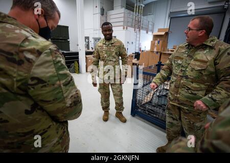 Staff Sergeant Salem Dogbe, Individual Equipment Element, 168th Wing Logistics Readiness Squadron, observes as fellow Airmen try on Operational Camouflage Pattern cold weather parkas at Eielson Air Force Base, Alaska, June 6th, 2021. Airmen from the 168th Wing, Alaska Air National Guard, are being issued their OCP cold weather parka, a vital part of their uniform when operating in an arctic environment. LRS is tasked with ensuring the Airmen of the 168th Wing are supplied with the clothing and equipment they require for mission success, especially in the sub-zero temperatures of Alaska. Stock Photo