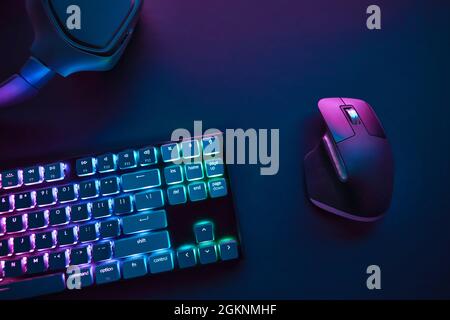 View of pastel neon color backlighted computer keyboard and mouse from above. Professional computer game playing, esport business and online world con Stock Photo