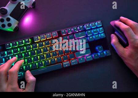 Close-up of male hands using color backlighted keyboard and mouse. Professional computer game playing, esport business and online world concept. Stock Photo