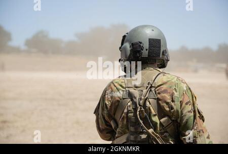 A UH-60 Blackhawk kicks up dust as Staff Sgt. Kyle Sanders with Golf Company, 1-189th Aviation Regiment, Oregon Army National Guard performs a safety check on his communications equipment prior to conducting the hot-load portion of MedEvac training at Fort Hunter Liggett, Calf. June 7, 2021. During a hot-load exercise, pilots perform the pre-flight safety checks and ensure that the blades are running while the aircraft remains stationary throughout the loading of casualties to simulate a combat environment. The training took place during Global Medic, a sub exercise  of the Combat Support Trai Stock Photo