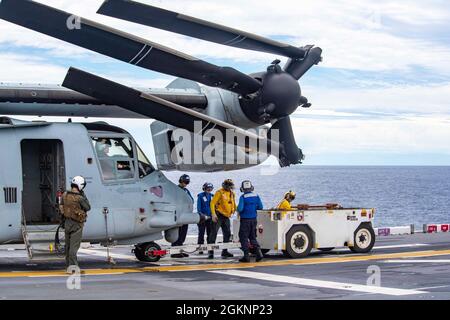 PHILIPPINE SEA (June 7, 2021) Sailors assigned to the forward-deployed amphibious assault ship USS America (LHA 6) prepare to tow an MV-22B Osprey attached to the 31st Marine Expeditionary Unit, Marine Medium Tiltrotor Squadron (VMM) 265 (Reinforced) on the ship’s flight deck. America, lead ship of the America Amphibious Ready Group, along with the 31st MEU, is operating in the U.S. 7th Fleet area of operations to enhance interoperability with allies and partners and serve as a ready response force to defend peace and stability in the Indo-Pacific region. Stock Photo