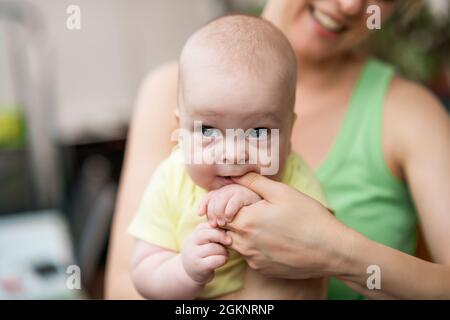 Portrait  of cute little baby boy holding  mother's   finger  in  his mouth. Stock Photo