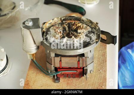 Repair Service Worker. Repairman is opening the old dishwasher machine. Repair service concept. Dishwasher machine repair process. Scale on metal part Stock Photo